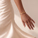 Modelka w kremowej satynowej sukience z personalizowaną złotą bransoletką bangle z grawerowaną datą