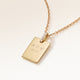 Personalised square gold necklace with white zirconia seen from the side, with initials, a heart and a year engraved on the front