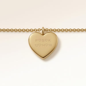 Close-up of minimalist heart-shaped heart pendant in gold with smooth surface and space for personalized engraving on the front and back