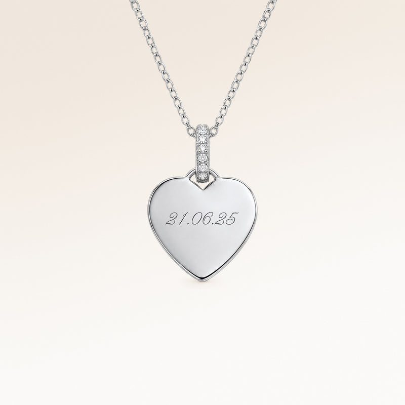 Close-up of minimalist heart-shaped heart pendant in silver with white zircons and space for personalized engraving on the front and back