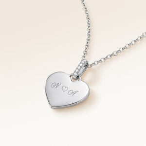 Angled close-up of minimalist heart-shaped heart pendant in silver with white zircons and space for personalized engraving on the front and back