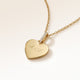 Close-up of minimalist heart-shaped heart pendant in gold with white zircons and space for personalized engraving on the front and back