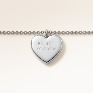 Close-up of minimalist heart-shaped heart pendant in silver with smooth surface and space for personalized engraving on the front and back