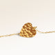 Close-up of minimalist heart-shaped heart pendant in gold with rippled wave surface and space for engraving on back
