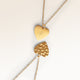 Close-up of minimalist heart-shaped heart pendant in gold with rippled wave surface and space for engraving on back
