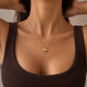 Model lifting her hair, wearing a heart-shaped gold necklace with a rippled wave surface and space for personal engraving of text, coordinates or handwriting on the back