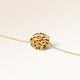 Close-up of minimalist round pendant in gold with rippled wave surface and space for engraving on back