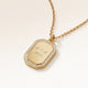 Close-up of an octagon gold pendant with white zirconia around the edge and a personal engraving of initials with a heart and a year