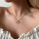 Personalized heart-shaped gold necklace with ribbed sunburst pattern and space for engraving of text or coordinates on the back