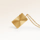 Close-up of minimalist square pendant in gold with ribbed sunburst surface and space for engraving on back