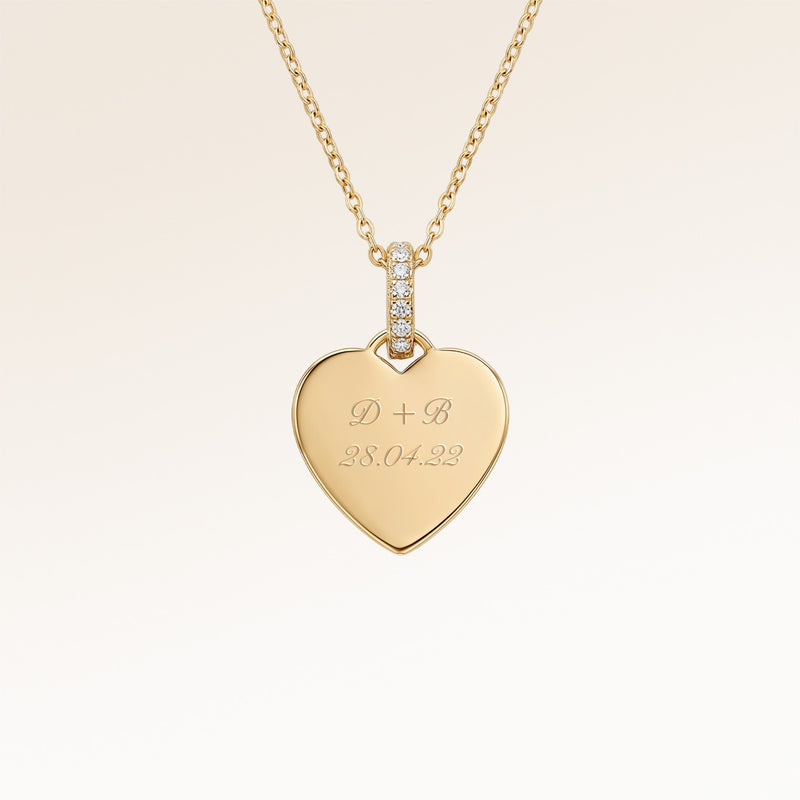 Close-up of minimalist heart-shaped heart pendant in gold with white zircons and space for personalized engraving on the front and back